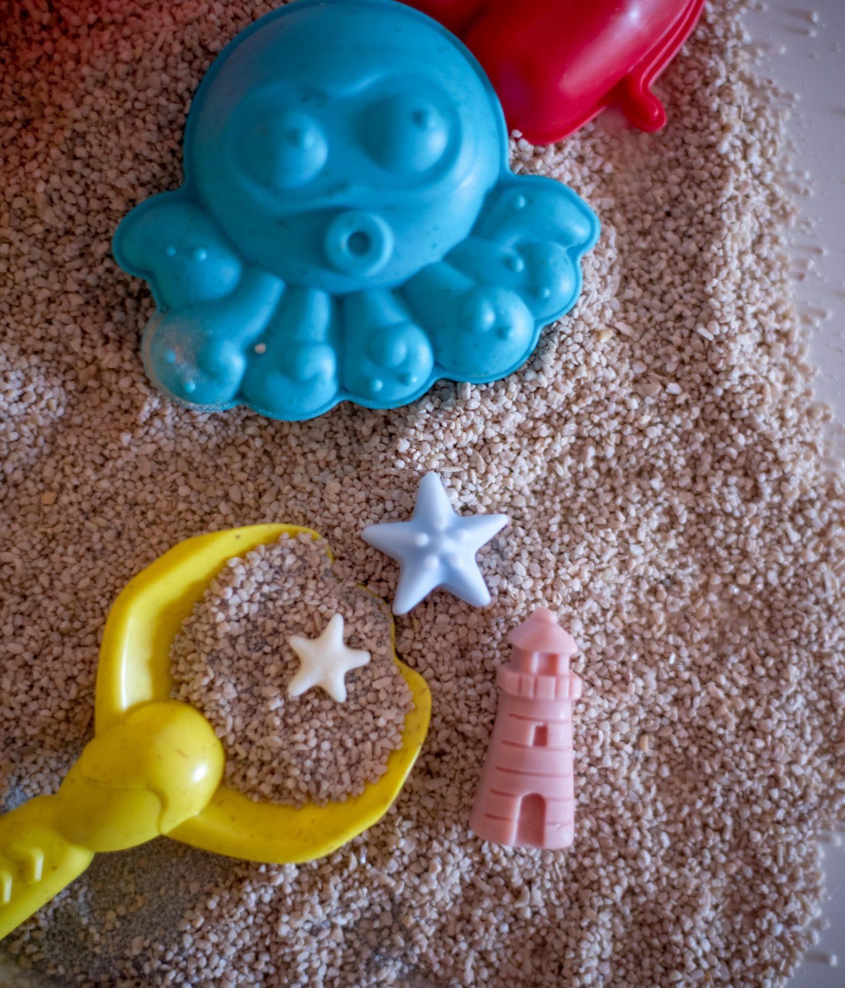 Ljetni mirisni vosak Summer Jam u obliku papuča, lopte i sunca, postavljen na pijesku s kantom i lopaticom