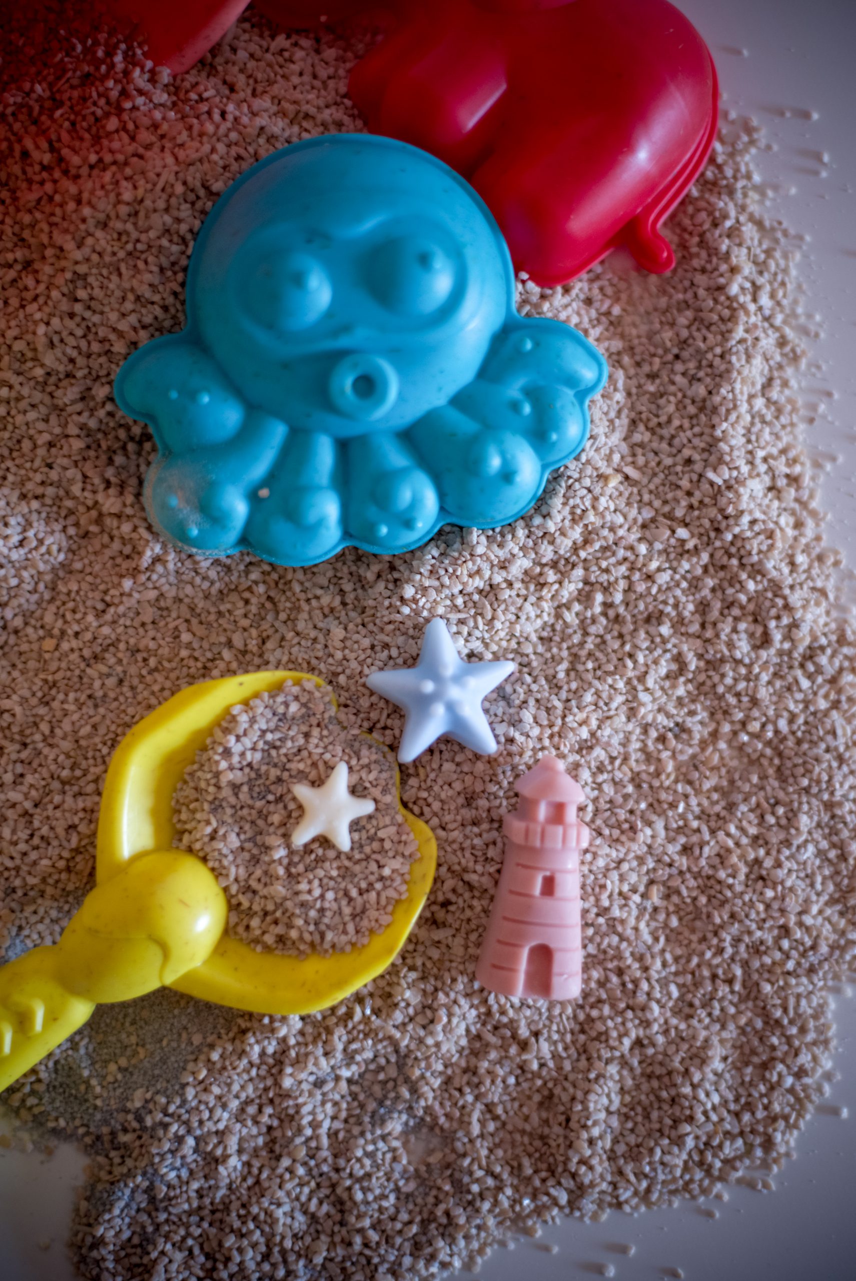 Ljetni mirisni vosak Summer Jam u obliku papuča, lopte i sunca, postavljen na pijesku s kantom i lopaticom